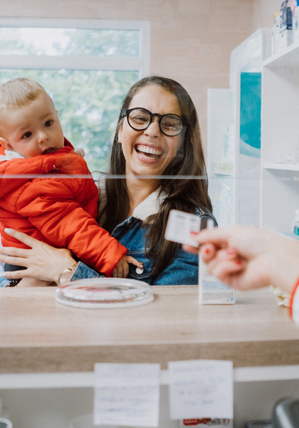 A member smiling, holidng a child and taking back their insurance card