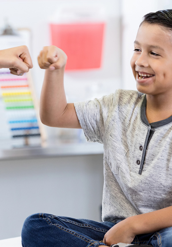 A child smiling in doctors office, fist bumping provider