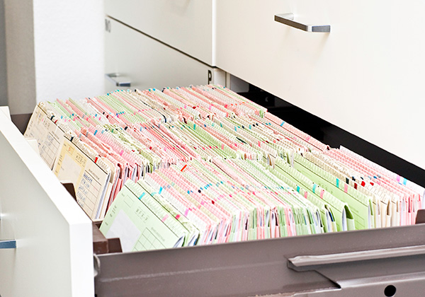 An open drawer on a file cabinet filled with multicolor organized file folders and documents.