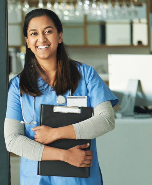 Young female provider smiling holding a clipboard clasped to their chest in a welcoming manner.